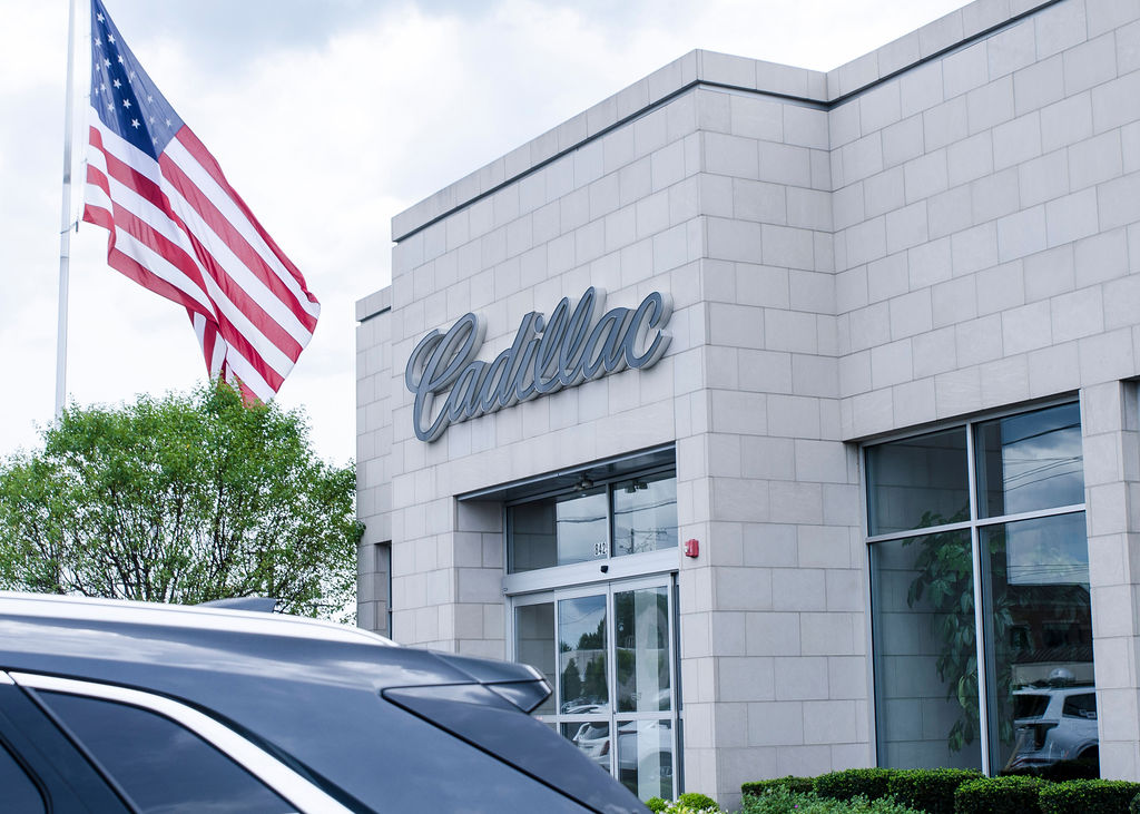American flag flying beside the Cadillac sign on the Rizza Cadillac building