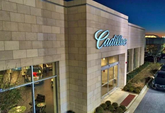 The Rizza Cadillac building with its Cadillac sign lit at dusk